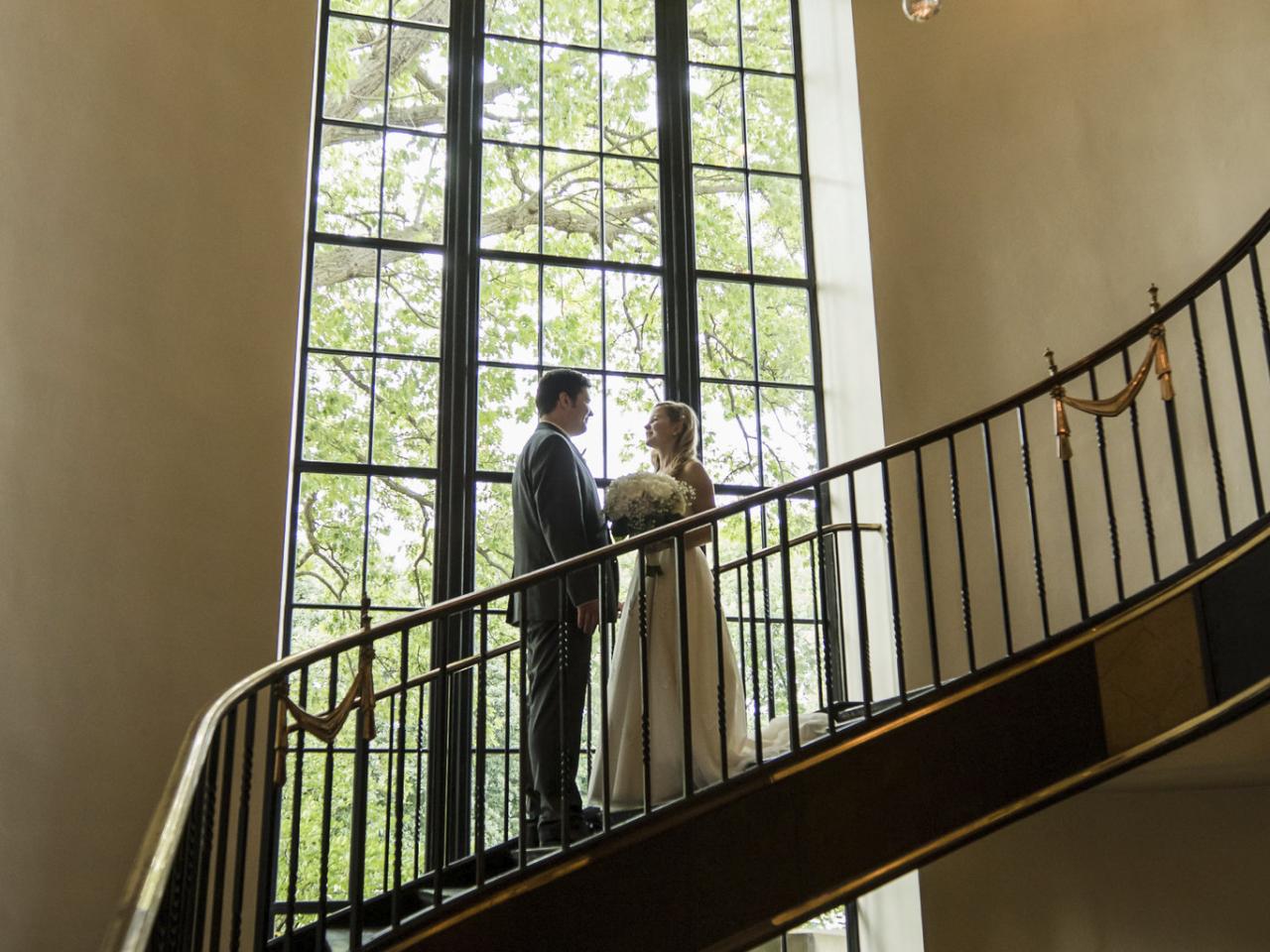 Couple posed on staircase beneath chandelier during wedding at faculty club