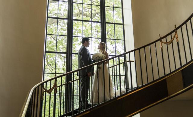 Couple posed on staircase beneath chandelier during wedding at faculty club